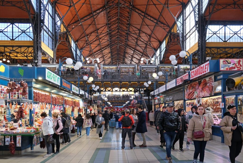 Crowds of visitors navigate the vibrant Central Market Hall in Budapest, Hungary, showcasing a lively indoor market atmosphere