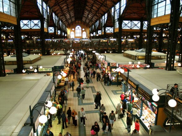 A bustling Central Market Hall in Budapest, Hungary, filled with people exploring various stalls and shops