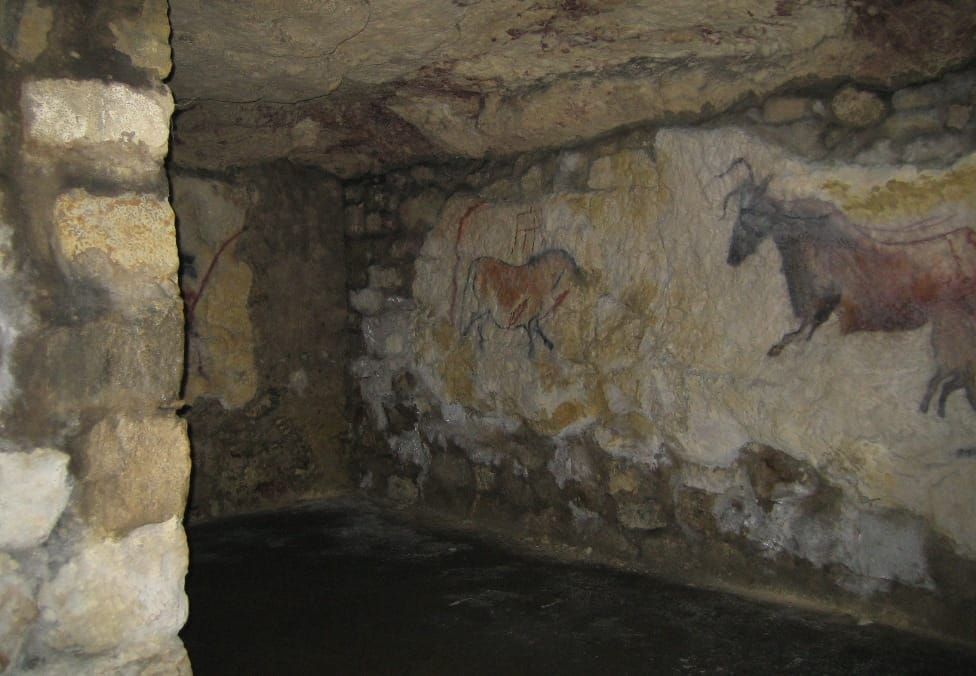 Buda Castle Cave – Underground stone chamber with ancient-style cave paintings of animals on rough stone walls, evoking a prehistoric atmosphere
