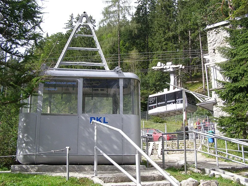 Exterior view of the Kasprowy Wierch Cable Railway – Ground Station in Kuźnice, Zakopane, Poland, with visitors lining up for tickets beneath the Tatra Mountains.