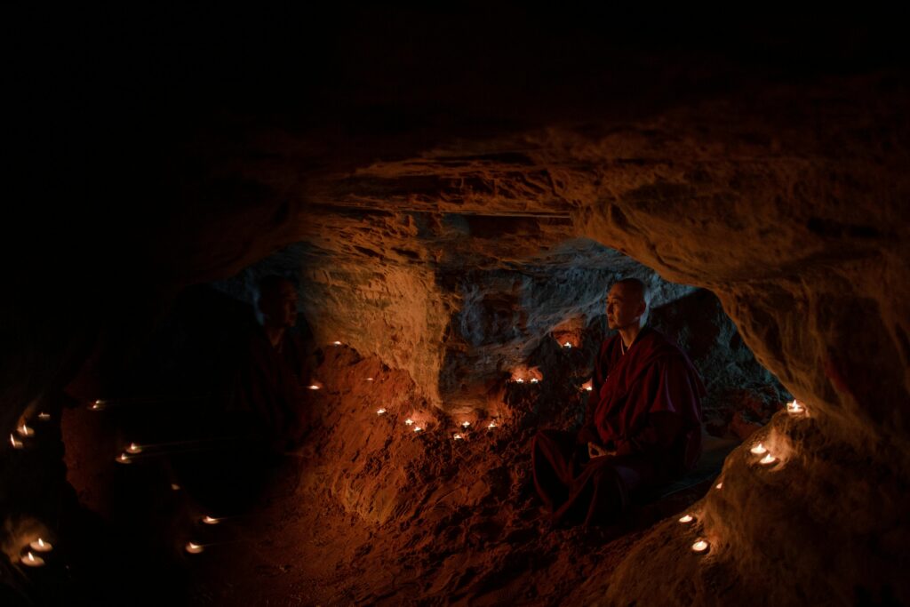 candles illuminating frescoes inside a small cave church in Matera Italy