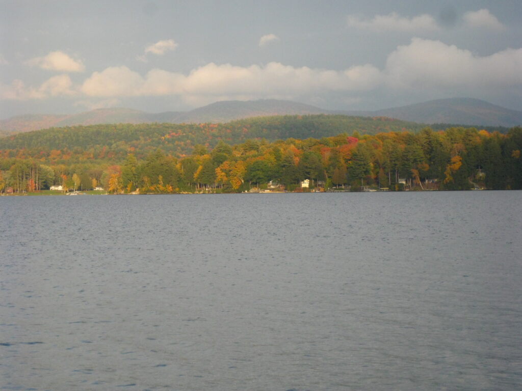 Scenic view of Lake Bomoseen in Vermont with calm blue water, surrounding green mountains, and a peaceful lakeside atmosphere — one of the best lakes in Vermont for swimming and outdoor activities.