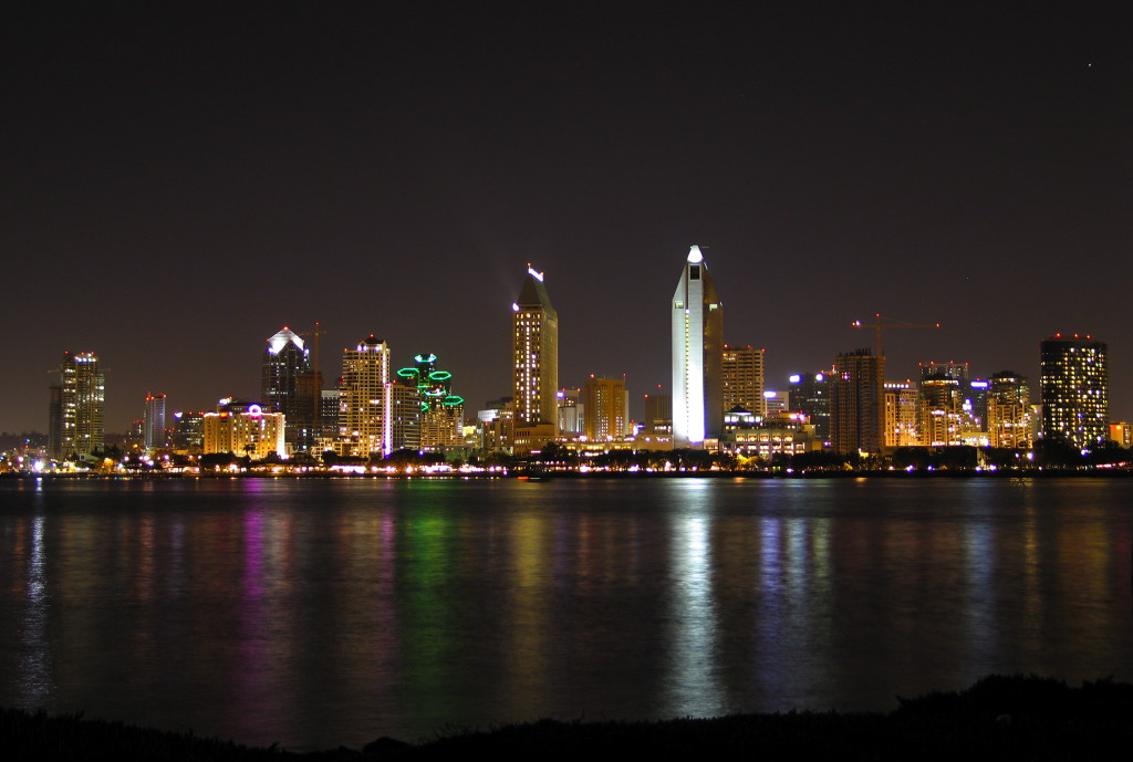 Illuminated San Diego downtown skyline at night with lights reflecting in San Diego Bay California