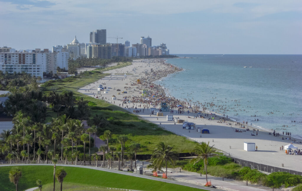 "View of Miami Beach from South Pointe Park showing white sand, turquoise water, and crowds enjoying the ocean — a perfect example of top things to do in Miami Beach like sunbathing, swimming, and beachfront strolls