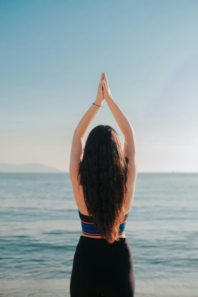 Person practicing yoga by the ocean during sunrise — one of the relaxing things to do in Miami Beach for wellness and mindfulness by the sea.