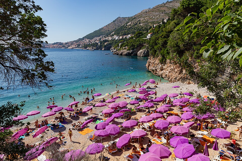 Sveti Jakov Beach in Dubrovnik with a pink umbrella on the sand, a serene spot perfect for relaxation and one of the best things to do in Dubrovnik away from the crowds