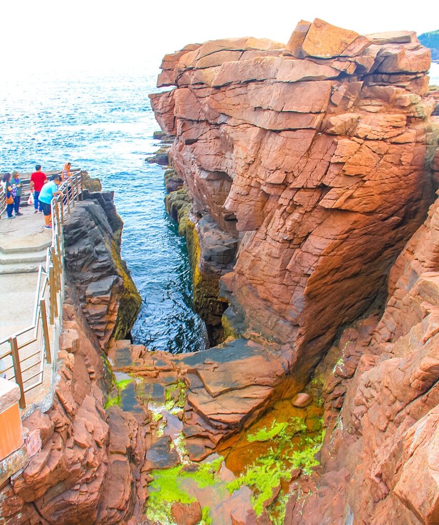 Acadia Hikes at Thunder Hole featuring travelers exploring dramatic red cliffs and ocean views along the Acadia National Park coastline