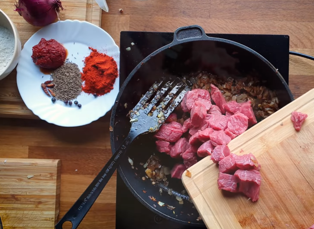 Beef chunks coated in vibrant red paprika mixture for Czech goulash