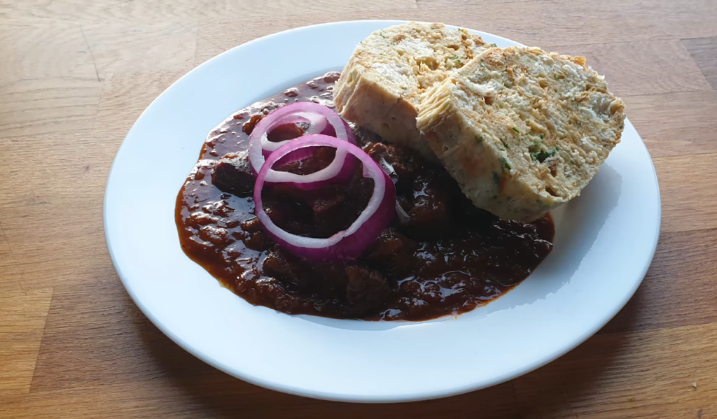  A plate featuring a sandwich alongside a serving of Czech goulash meat