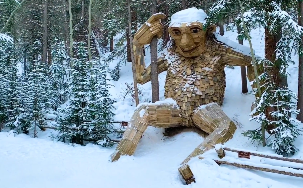 Breckenridge troll sculpture in winter, a giant wooden troll sitting in a snowy forest near Breckenridge, Colorado