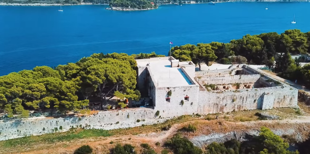 Aerial view of the historic British Fort on Vis Island, Croatia, surrounded by pine forests and overlooking the blue Adriatic Sea