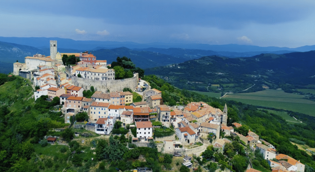Aerial drone view of Motovun, Croatia, showing the hilltop medieval town, stone walls, and surrounding Istrian countryside