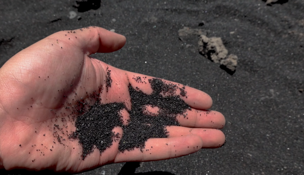 Close up of fine black volcanic basalt sand at Punaluu Beach showing texture and grain detail