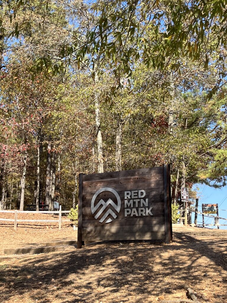 Entrance sign at Red Mountain Park surrounded by fall trees, highlighting one of the top things to do with family in Birmingham AL