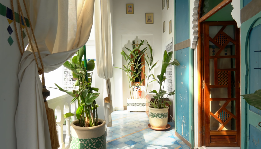 Sunlit balcony at Riad Malfa Marrakesh with potted plants, tiled floor, and traditional wooden doorway