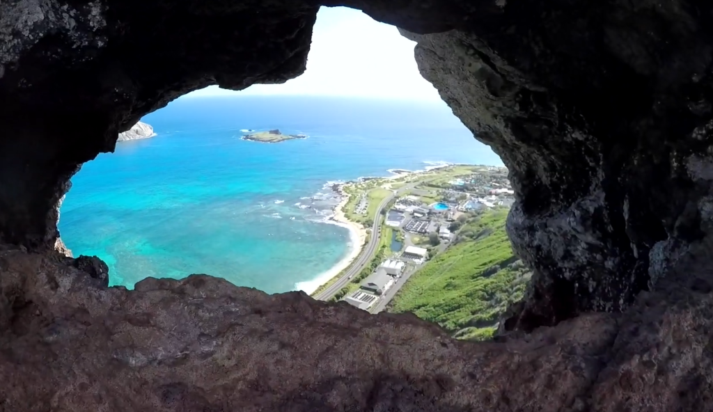 Tom Tom Trail hike on Oahu with ocean views through a cave opening overlooking the coastline, one of the best hikes on Oahu