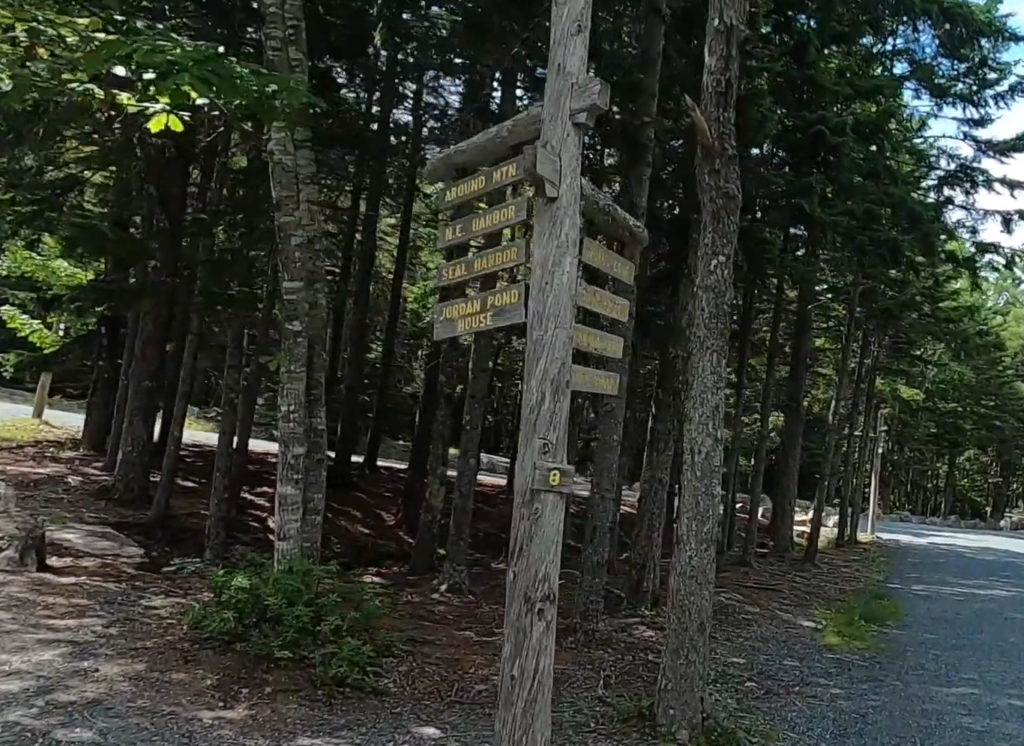 Trail junction at northern end of jordan pond path trailhead showing Carriage Road intersection and trail signs