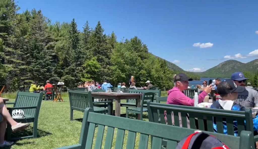 View of jordan pond path trailhead and Bubbles mountains from Jordan Pond House restaurant outdoor seating area